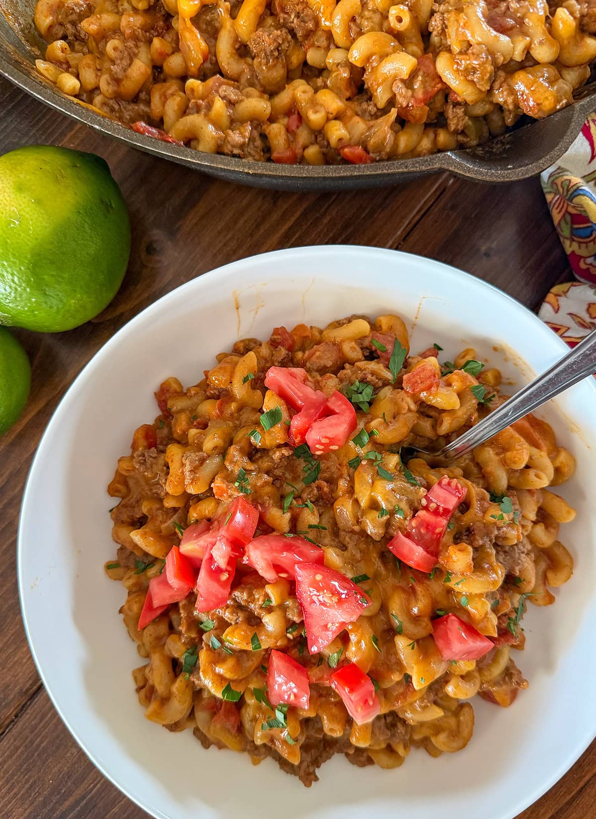 taco mac and cheese in a skillet with lime slices.