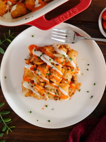 Buffalo chicken tater tot casserole with sauce and ranch dressing.
