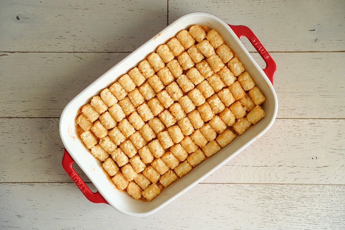 a layer of tater tots over chicken casserole in a baking dish.