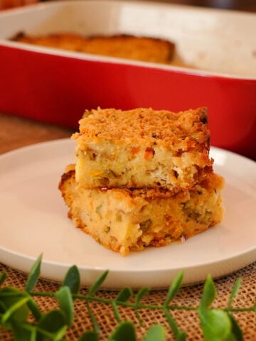 Cornbread slices on a plate next to a baking dish.