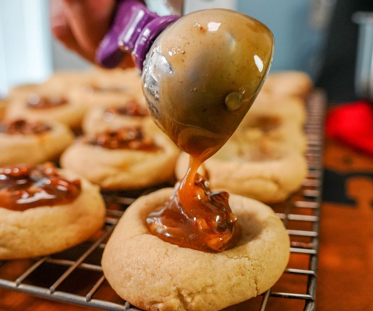 pecan filling being scooped on top of cookies.