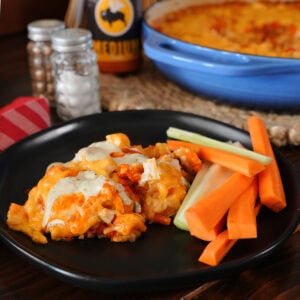 A buffalo chicken casserole on a plate with carrots and celery.
