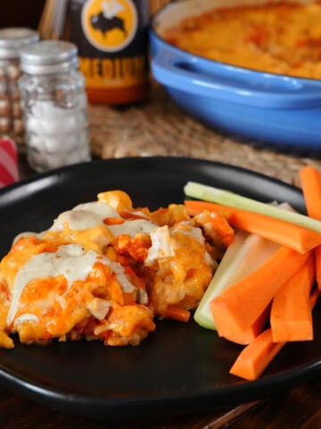 A buffalo chicken casserole on a plate with carrots and celery.