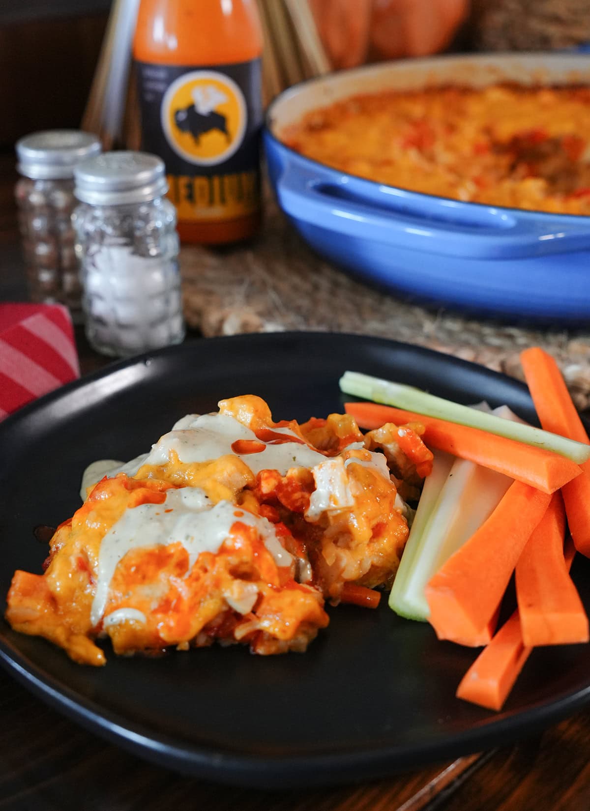 A scoop of buffalo chicken casserole on a plate with carrots and celery