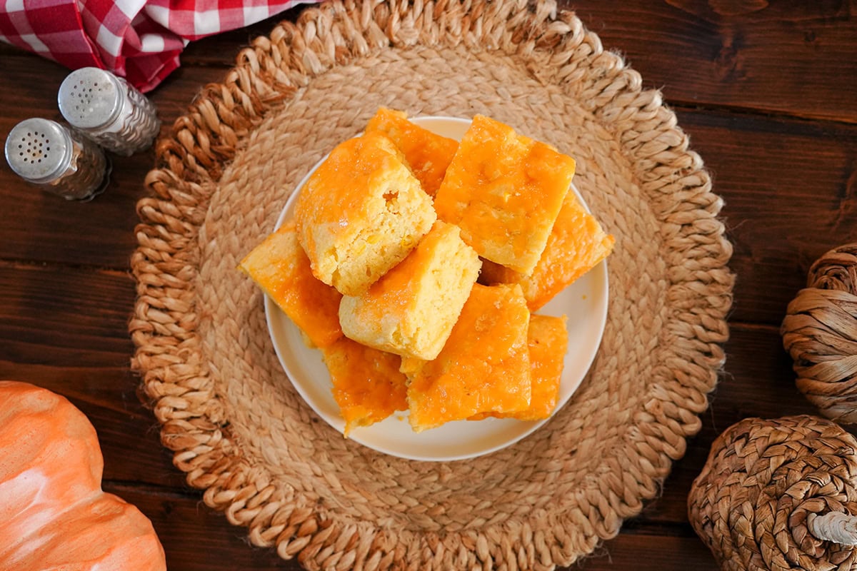 Cheesy cornbread squares next to fall decor and salt and pepper.