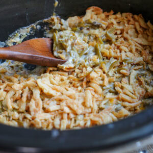 a wooden spoon in a slow cooker with green bean casserole.