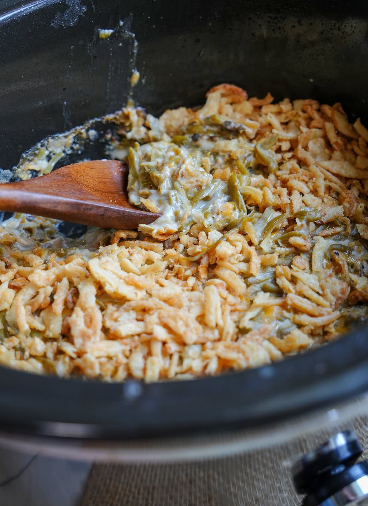 Green bean casserole in a crock pot with a French onion topping.