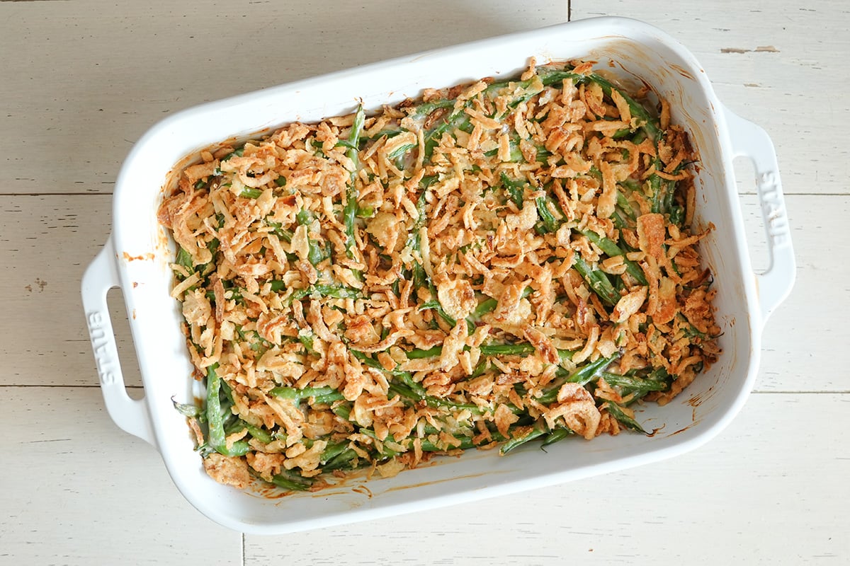 a green bean casserole with bacon in a baking dish topped with fried onions.