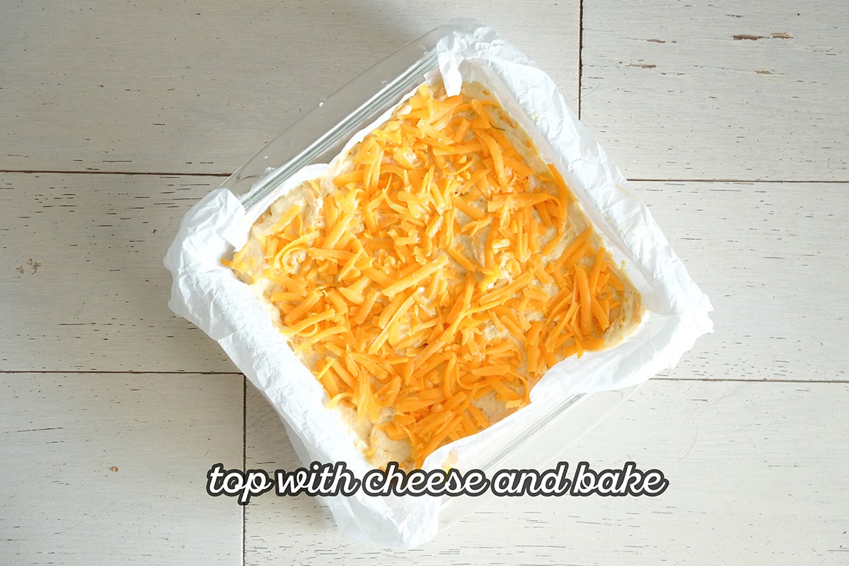 cornbread batter in a baking dish topped with cheese.