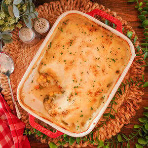 Chicken shepherds pie in a red baking dish with chives.