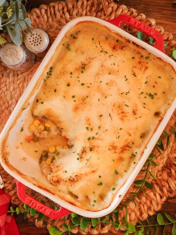 Chicken shepherds pie in a red baking dish with chives.