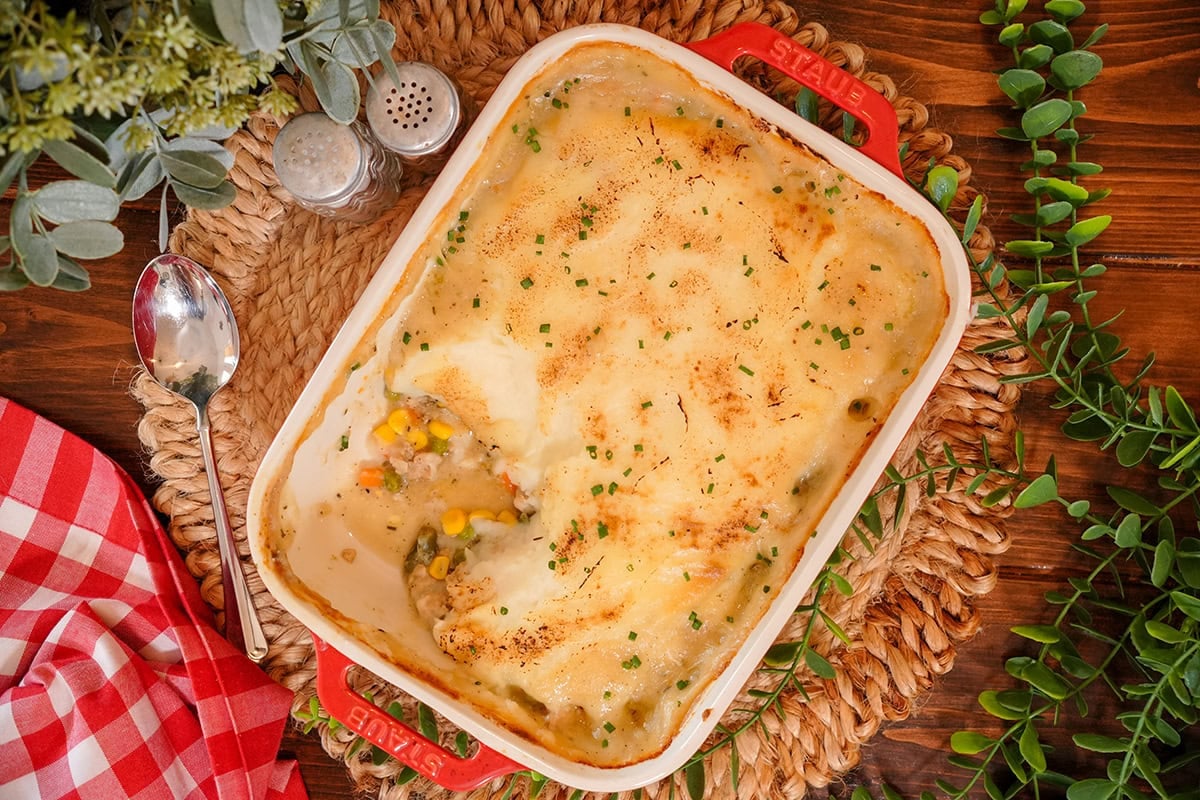 chicken shepherds pie in a baking dish surrounded by greenery.