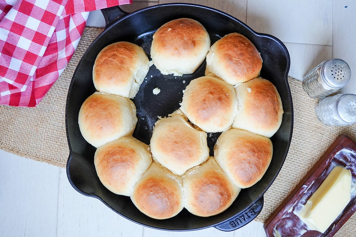 golden easy yeast rolls in a skillet next to butter and salt.