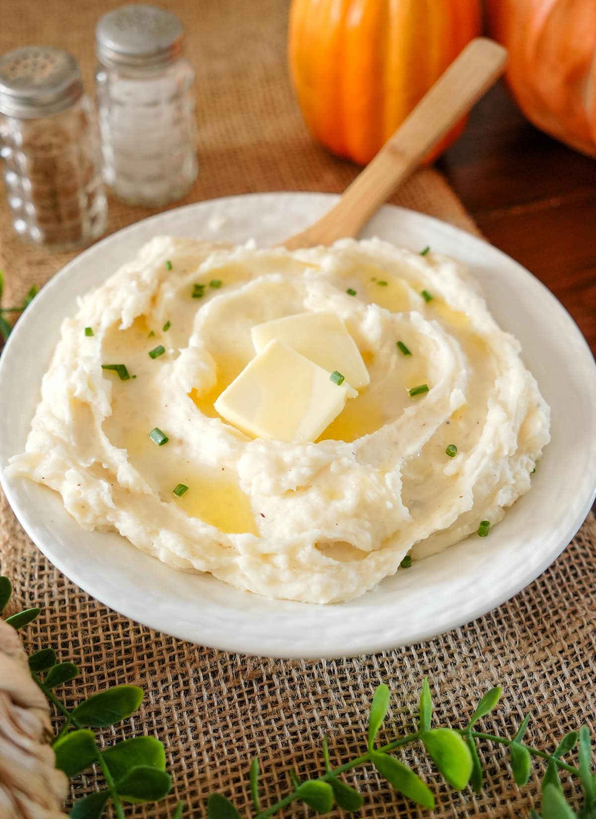 Mashed potatoes in a bowl with melted butter and chives.