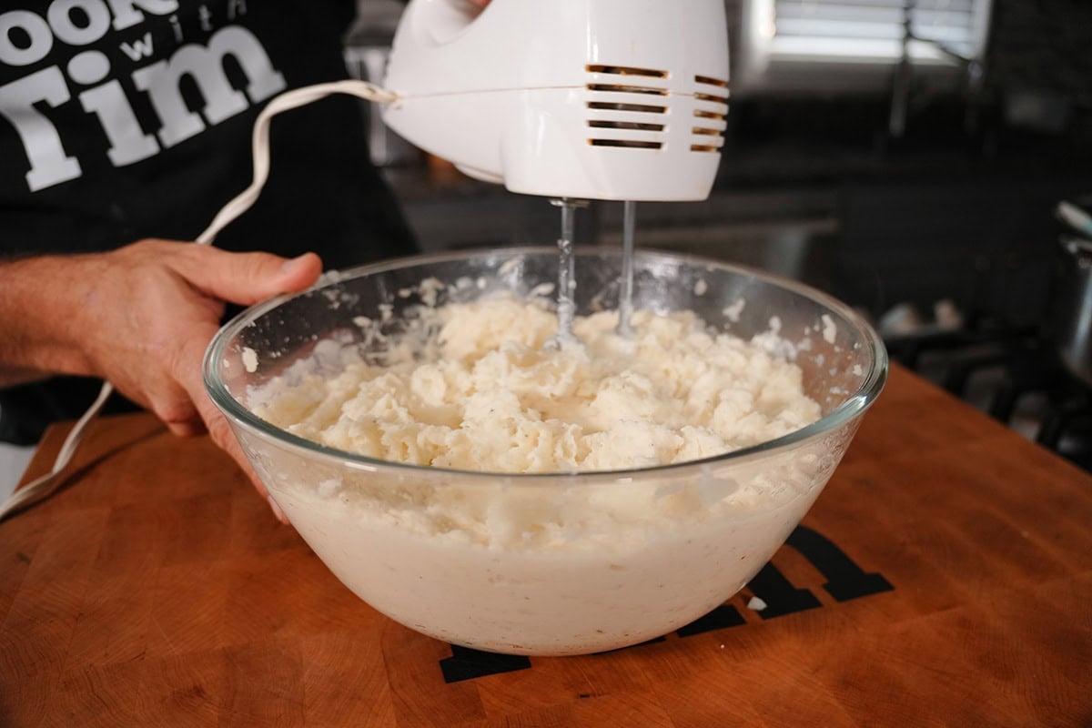 mashing potatoes with a hand mixer.
