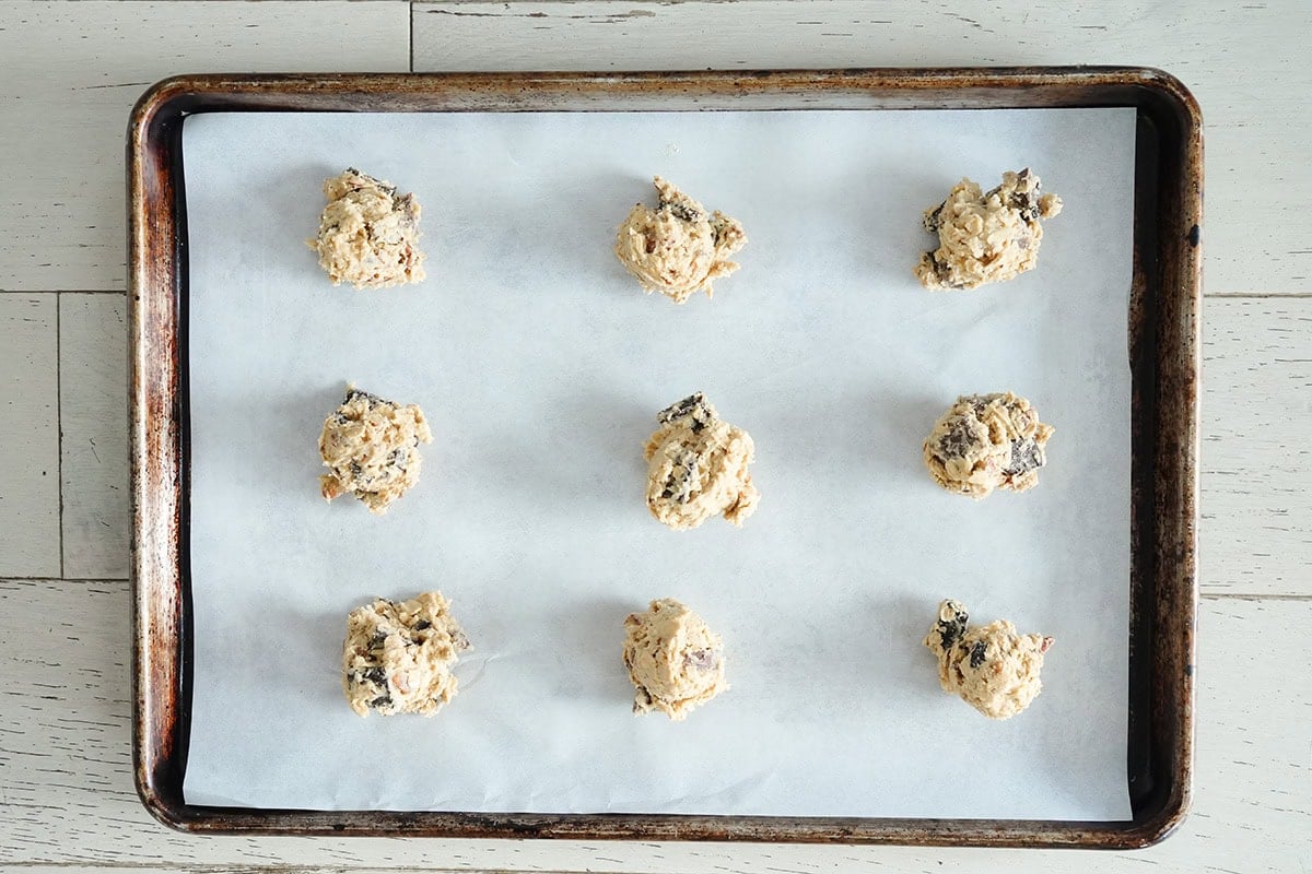 9 cookie dough balls on a baking sheet.