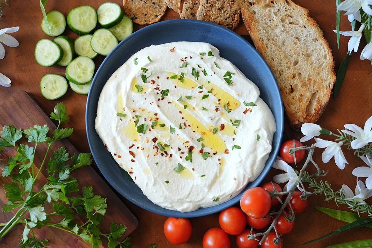 whipped feta on a plate with vegetables and crackers.