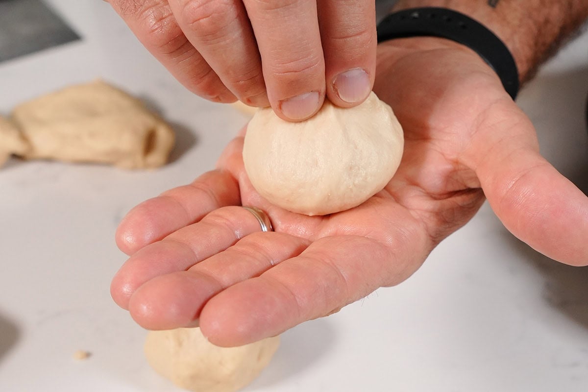 a hand rolling up a dough ball.